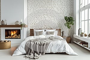 Bed with pillows and coverlet near fireplace against white brick wall. Loft, scandinavian interior design of modern bedroom.