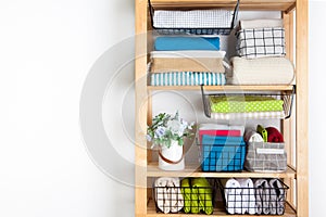 Bed sheets, duvet covers and towels are folded vertically. Metal and fabric black baskets. Bedclothes bright colors