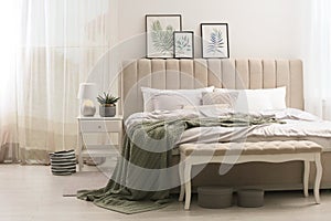 Bed with stylish grey linens near white wall in room