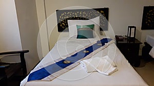 Bed with white bedding, decorated with pillow and blue Bed runner