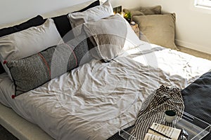 A bed with a white comforter and black and white pillows