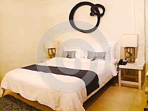 The bed with white fabric. There are may pillows against the wall and the wooden lamp with two sides of bed. The wall was