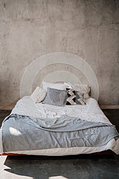 bed with white and grey linens against the background of the wall.