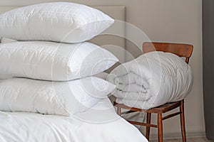 A bed with white pillows and a blanket, next to a bedside table with a lamp