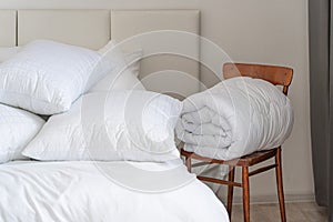 A bed with white pillows and a blanket, next to a bedside table with a lamp