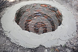 Bedding mortar, cementing the edge of a  brick built manhole, septic tank, sewage system before plastic manhole cover, cap