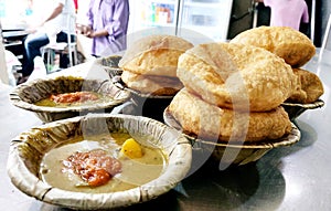 Bedmi puri and potato curry kept in a leaf container (Dona) on the table
