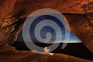 Bedouin in the Crimean cave Kachi-Kalyon is heated by the fire on the background of the starry sky