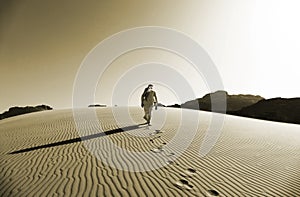 Bedouin Walking on the Sand Dunes in Wadi Rum Desert, Jordan in Sepia Colour