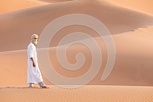 Bedouin on way through sandy desert. Beautiful sunset with big dunes on Sahara, Morocco. Silhouette nomad man.