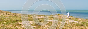 Bedouin in white robe overlooking the Atlantic ocean from dunes in Banc d Arguin National Park, Mauritania, North Africa