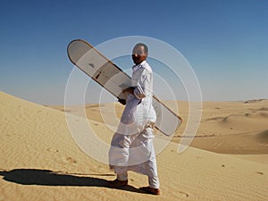 Bedouine man sand-boarding on dunes