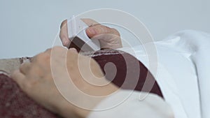 Bedridden female patient pushing nurse call button, suffering incurable disease