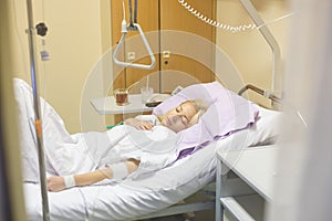 Bedridden female patient recovering after surgery in hospital care.