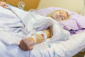 Bedridden female patient recovering after surgery in hospital care.