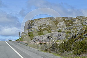 Bedrock cliff against blue sky along Newfoundland highway