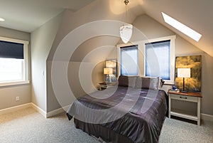 Bedroom with bed, bedside tables, vaulted ceiling, window coverings and accent lighting in contemporary upscale home interior