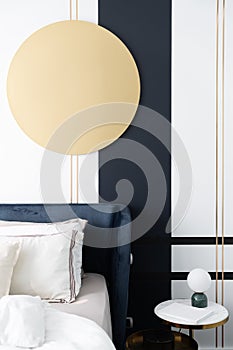 Bedroom corner navy blue velvet bed with soft pillows setting decorated with gold circular stainless and navy blue paint wall in