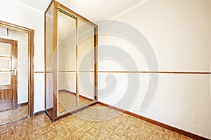 A bedroom with a custom-made wooden wardrobe with sliding mirror doors with metal edges and sintasol floors