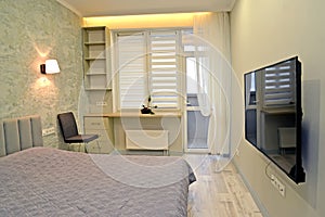 Bedroom with decorative window lighting and TV on the wall