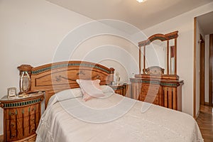 Bedroom with double bed with tacky wooden headboard in a room