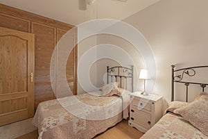 Bedroom with double beds with bedspreads and twin headboards and a wardrobe with Venetian-style wooden doors