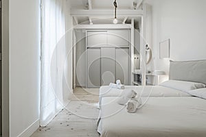 Bedroom with double beds joined together, white bedding, towels rolled