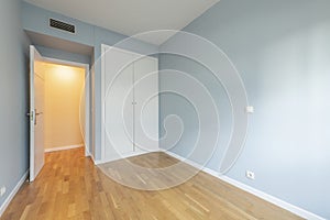 Bedroom of an empty house with laminated oak flooring with a white built-in wardrobe, ducted air conditioning and white carpentry photo