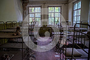 Bedroom with forgotten old doll in the kindergarten at the abandoned village Kopachi near Chernobyl