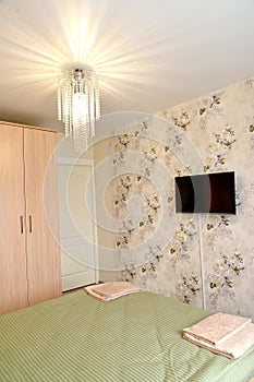 Bedroom interior with chandelier and TV on the wall