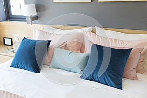 Bedroom interior with comfortable bed with pastel, blue and pink bedding