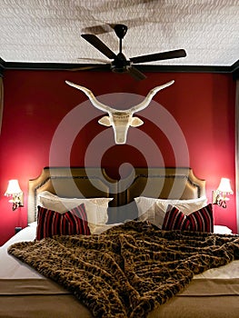 Bedroom interior at night. Africa safari style. Double bed, horns of buffalo.