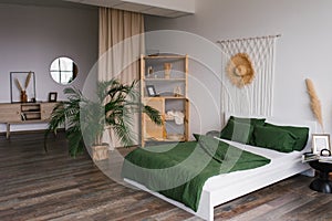 Bedroom interior in Scandinavian style. A bed with green linens, a potted date palm houseplant on the floor