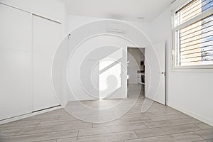 Bedroom in a loft-style home with a white built-in wardrobe, lime wood flooring and a sunny window