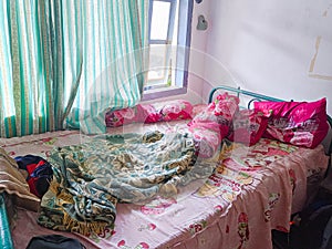 The bedroom is a mess. A child\'s room with a messy bed and pillows, bolsters and quilts that have not been tidied up.