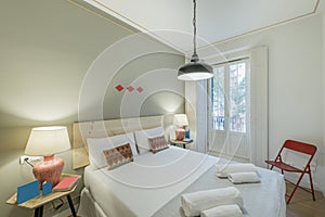 Bedroom with natural wood headboard, ethnic cushions, white towels