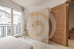 bedroom with oak wardrobe, balcony with large glass doors and white aluminum, access door of the same material and cream marble
