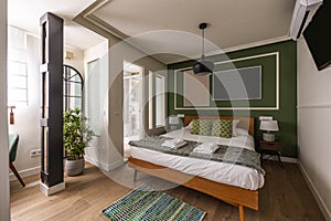 Bedroom with queen bed with green cushions, green wall