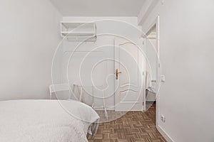 Bedroom with single bed with checkered slat parquet floor, donkey-type wardrobe, high shelves, lacquered wooden door and white