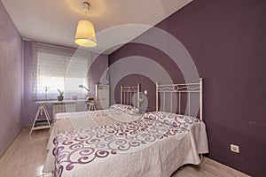 Bedroom with single beds with white metal headboards with patterned bedspreads in colors to match the walls and a study table