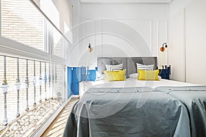 Bedroom with twin beds with headboards upholstered in gray fabric, assorted cushions and aluminum window on one wall