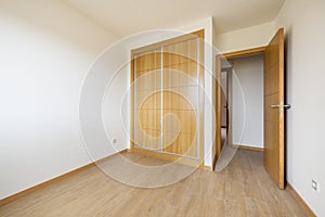 bedroom with two-section built-in wardrobe with large oak sliding doors and wooden floor and access door of the same material