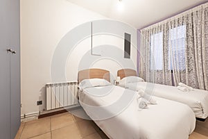 Bedroom with two single beds with light wood headboards, gray wardrobe