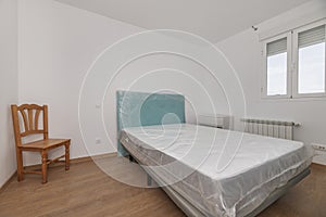 Bedroom with uninstalled bed with the protective plastics on photo