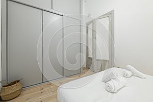 Bedroom with white bedding, rolled towels on the beds, gray sliding-door