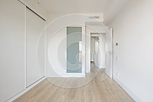 Bedroom with white built-in wardrobe, ducted air conditioning, white wood carpentry, oak-colored