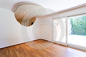 Bedroom with white walls and parquet. Arch with spotlights