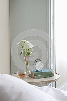 Bedside Table With Cut Flower And Alarm Clock