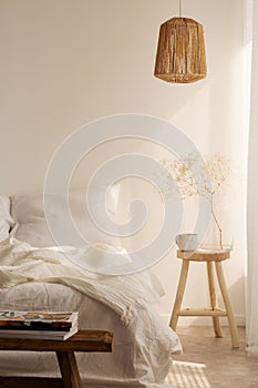 Bedside table with mug and flower next to bed, real photo with copy space