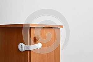 Bedside table wooden with baby proofing cabinet lock at home child safety photo